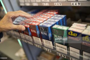 Packs of Pall Mall cigarettes manufactured by British American Tobacco Plc, sit in a display rack inside a news agents in London, U.K., on Friday, July 11, 2014. Reynolds American Inc., the producer of Camel cigarettes, said it's in talks to acquire Lorillard Inc. in a transaction that would create a closer competitor to U.S. tobacco market leader Altria Inc. Photographer: Simon Dawson/Bloomberg